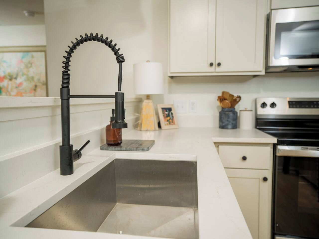 A kitchen with a modern faucet, a microwave, and a stove.