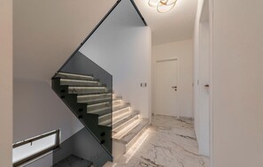 A modern interior with a glass staircase, white walls, and a marble floor. - Gorgeous home in Razanac (Razanac)