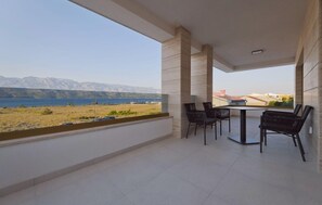 A balcony with a table and chairs, overlooking a body of water and distant mountains. - Gorgeous home in Razanac (Razanac)