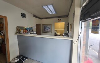 A reception area with a counter, a clock, and a 'No Smoking' sign.