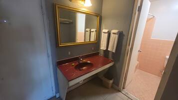 Een badkamer met een marmeren wastafel, een grote spiegel met gouden lijst en twee handdoeken aan de muur.