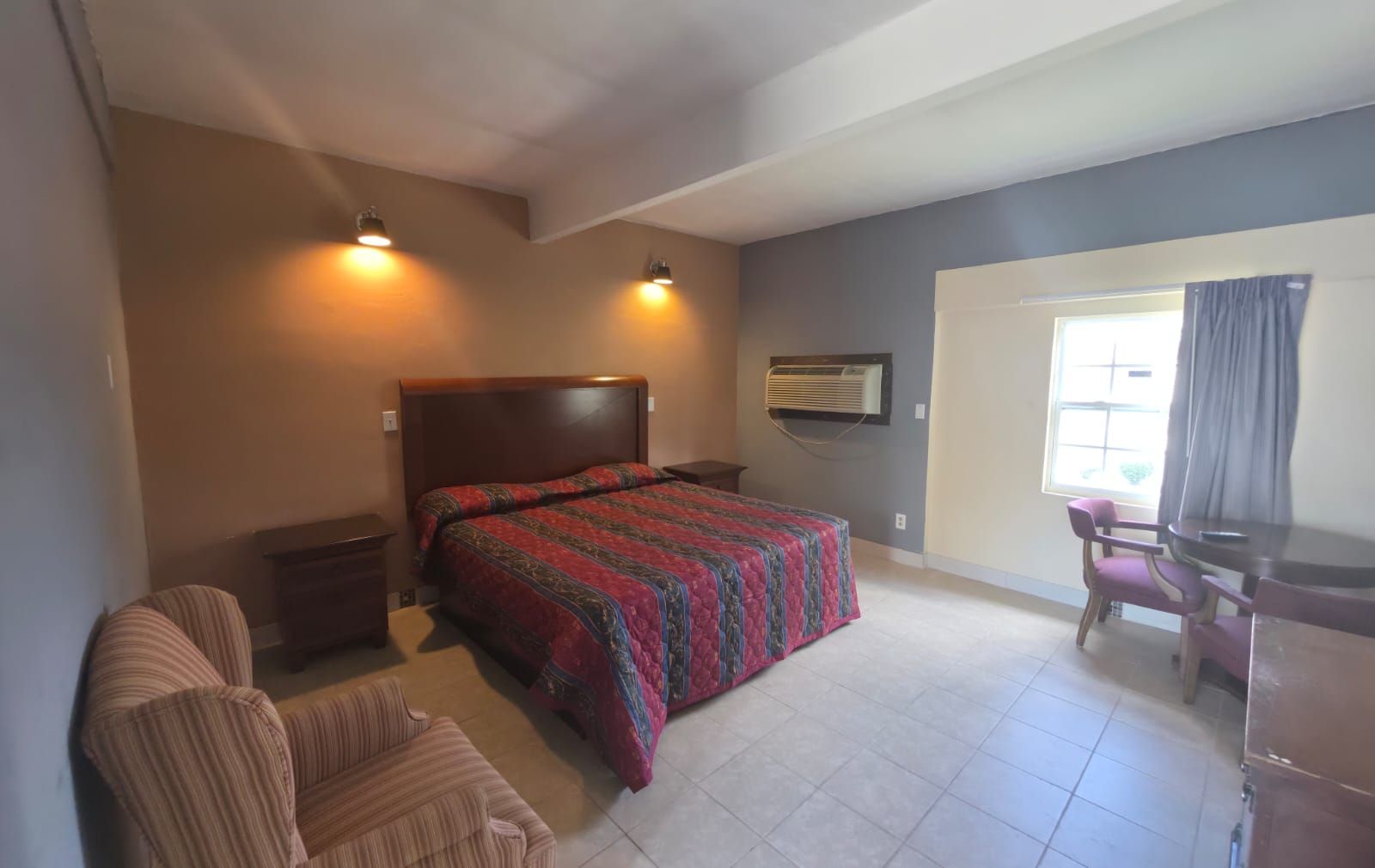 A bedroom with a bed, a desk, a chair, and a window.