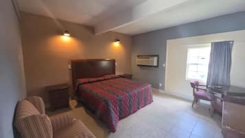 A bedroom with a bed, a desk, a chair, and a window.