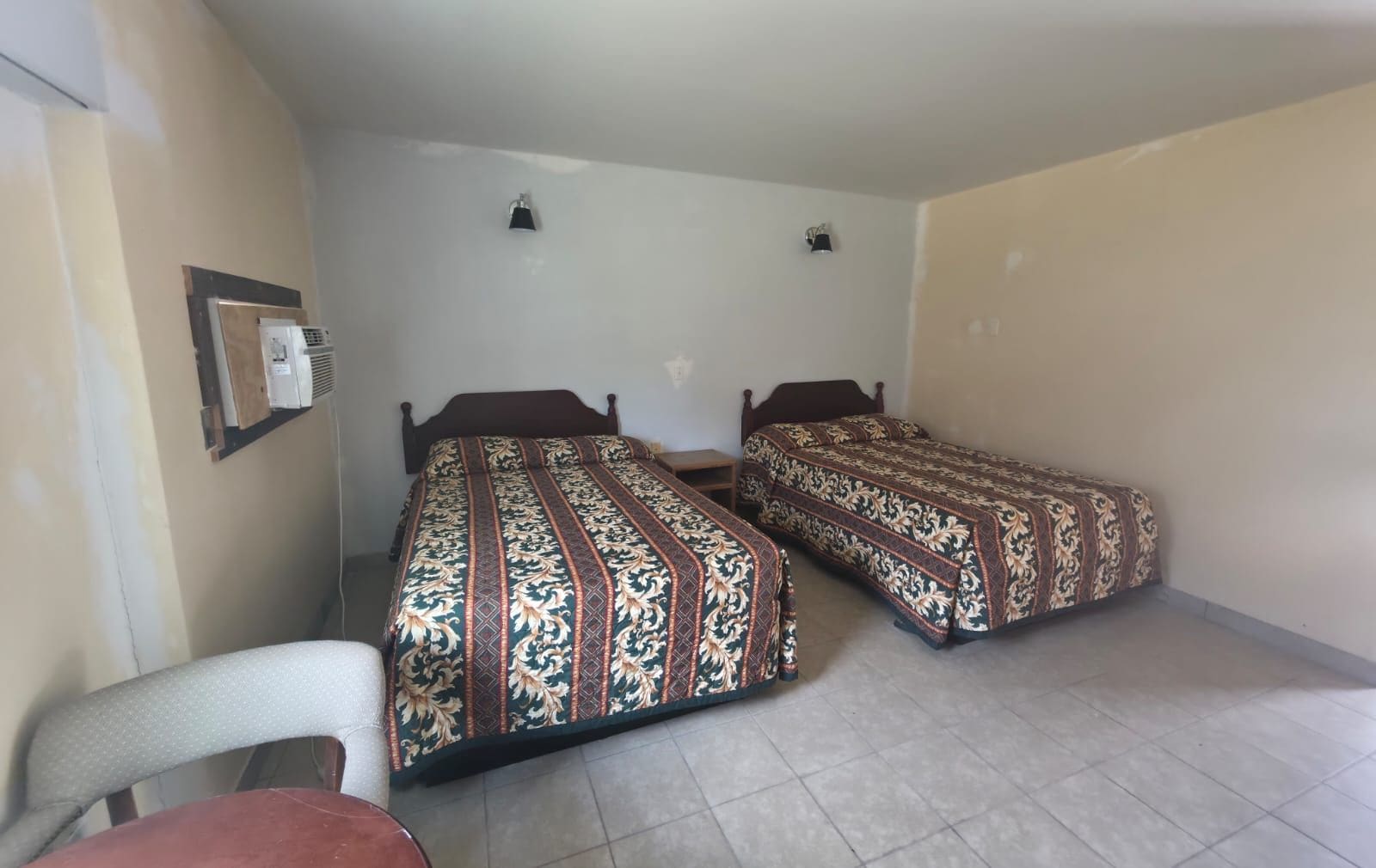 Une chambre avec deux lits, une chaise et un radiateur fixé au mur.