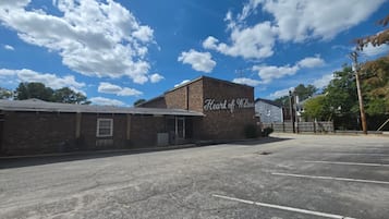 Un estacionamiento con un edificio identificado como 'Heart of Wilson' y un cielo azul despejado con nubes.