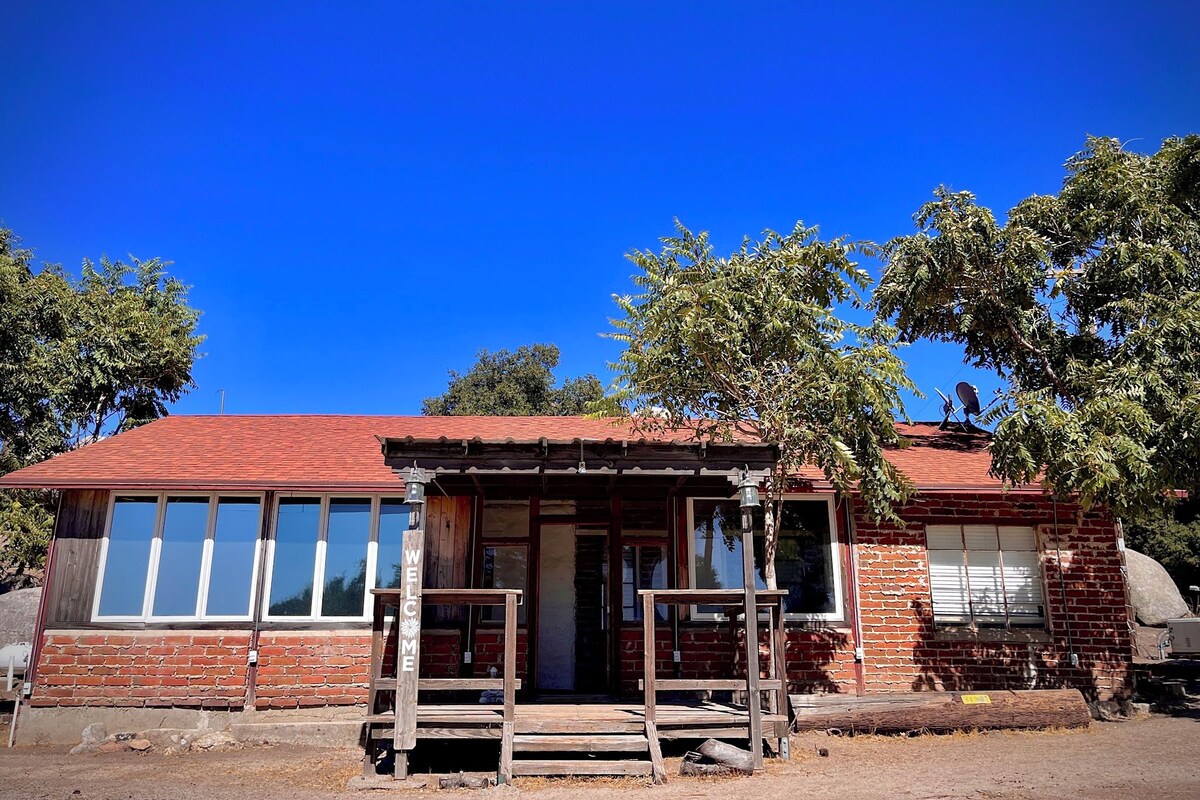 A rustic building with a red roof, a wooden porch, and a brick wall.