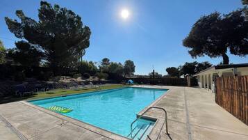 Una piscina rectangular con superficie de agua azul cristalina, rodeada por una solana de hormigón.