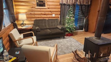 Et hyggeligt interiør i en træhytte med sofa, lænestol og pejs.