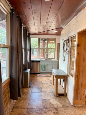 A kitchen with a built-in dishwasher, a sink, and a window with curtains.
