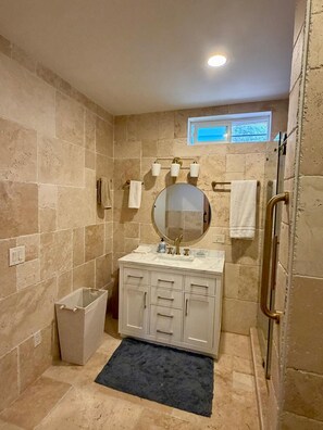 A bathroom with a shower, a sink with a mirror, and a towel rack. - Stagecoach Ranch (Boulevard)