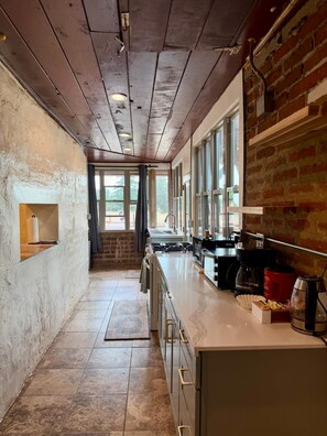 A kitchen with a long counter, a stove, and a coffee maker.