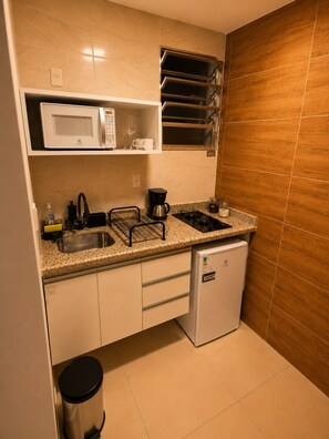 A compact kitchen with a microwave, coffee maker, sink, and a small refrigerator. - Estúdio Moderno a 50m Metrô Catete Perto da Praia (Rio de Janeiro)