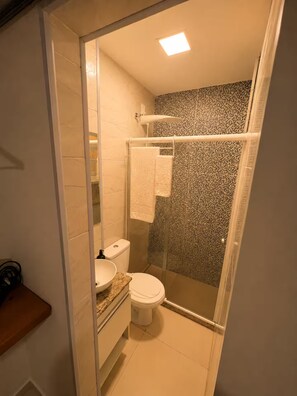 A bathroom with a toilet, sink, and shower area. - Estúdio Moderno a 50m Metrô Catete Perto da Praia (Rio de Janeiro)