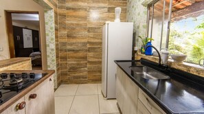 A compact kitchen with a gas stove, a refrigerator, and a sink. - Casa com 2 Quartos Varanda e Rede no Bela Vista (Itariri)