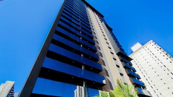 Un edificio alto y moderno con fachada de vidrio reflectante y varias balcones.