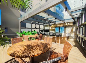 An outdoor seating area with tables and chairs, a stone wall, and a glass ceiling. - Connect Beira Mar (Fortaleza)