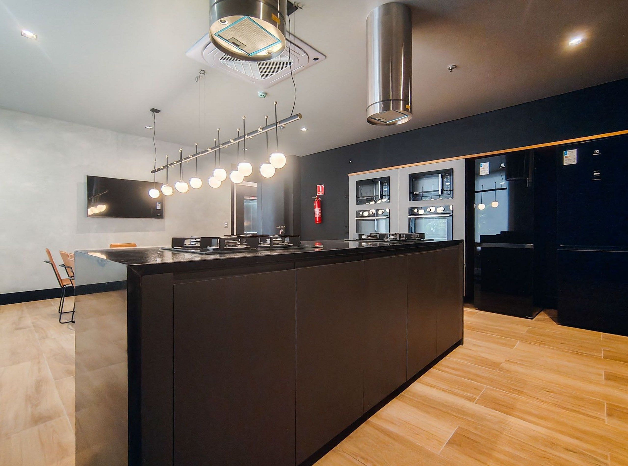 Una cucina moderna con isola centrale, forni integrati e illuminazione a sospensione.