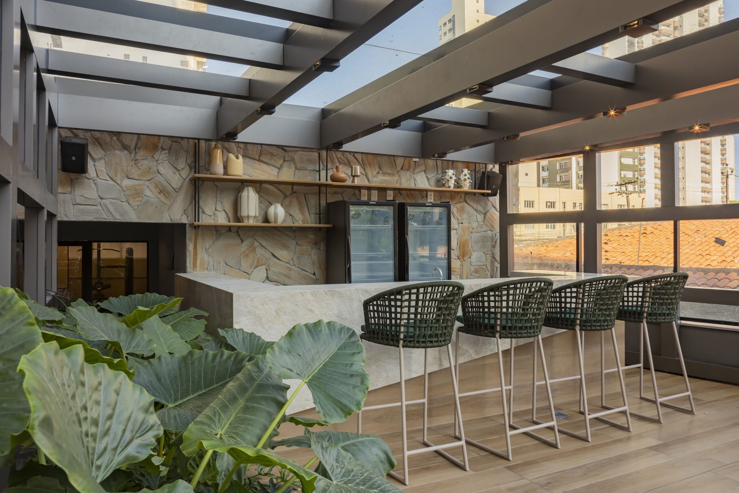 Un área de bar moderna con pared de piedra, taburetes y vistas de la ciudad.