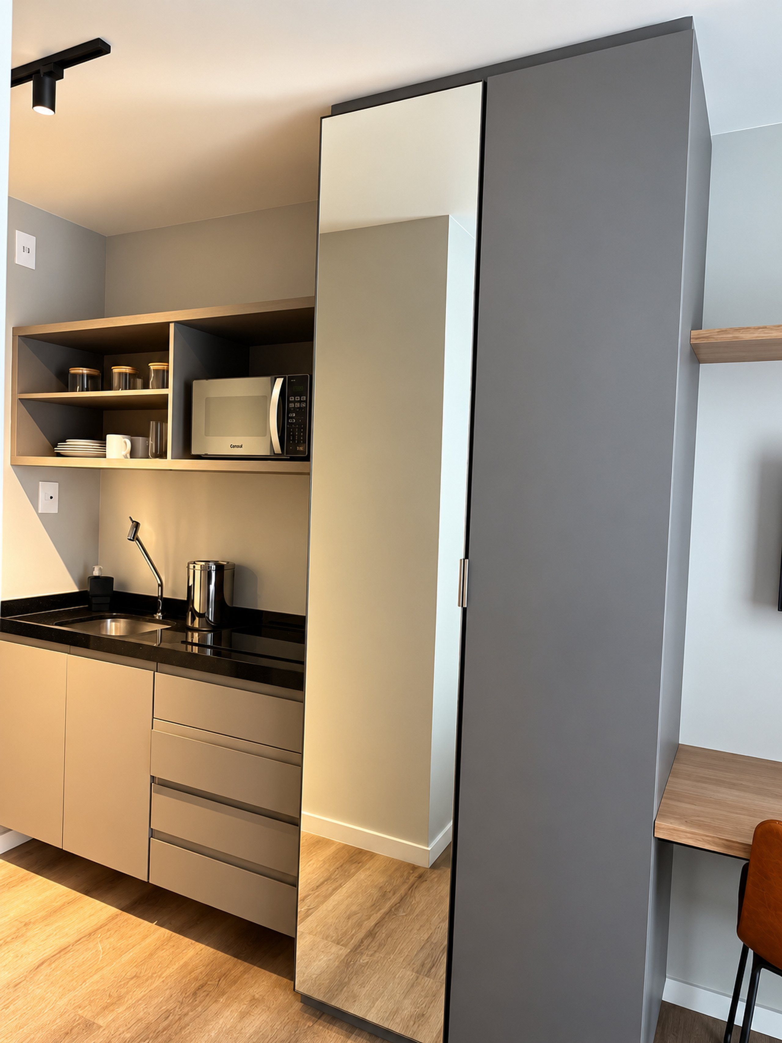 A modern kitchen with a microwave, shelves, and a wooden table.