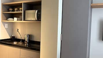 A modern kitchen with a microwave, shelves, and a wooden table.