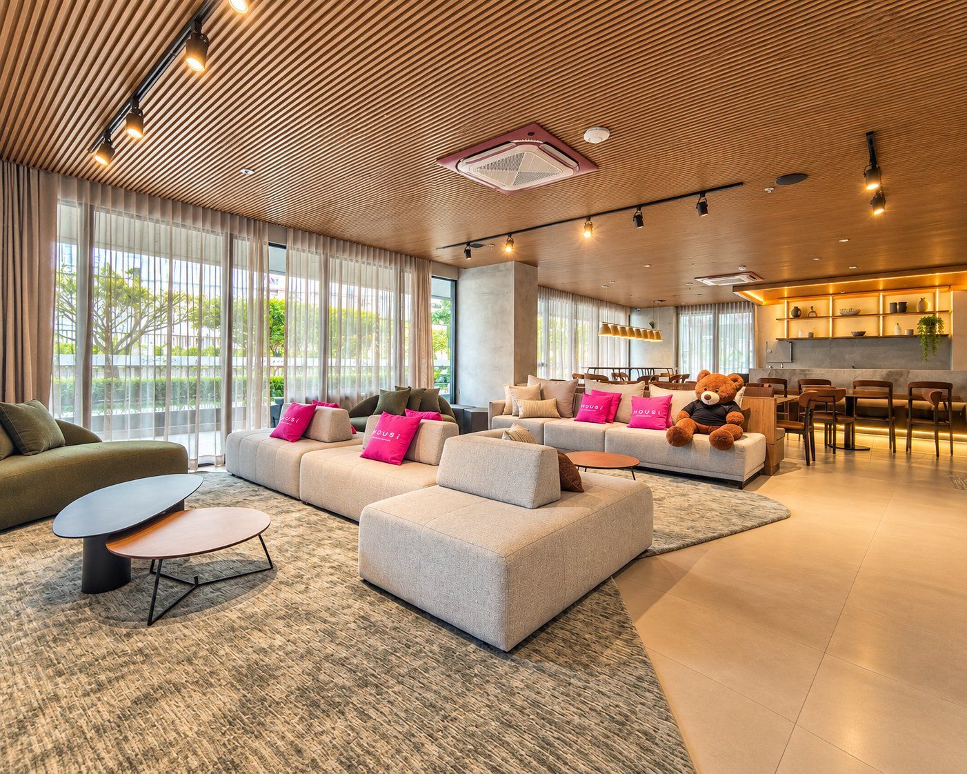 A modern hotel lobby with a seating area, a dining space, and a kitchen area.