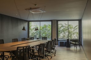 Una sala de conferencias moderna con una larga mesa, sillas y ventanas amplias que dan a zonas verdes.