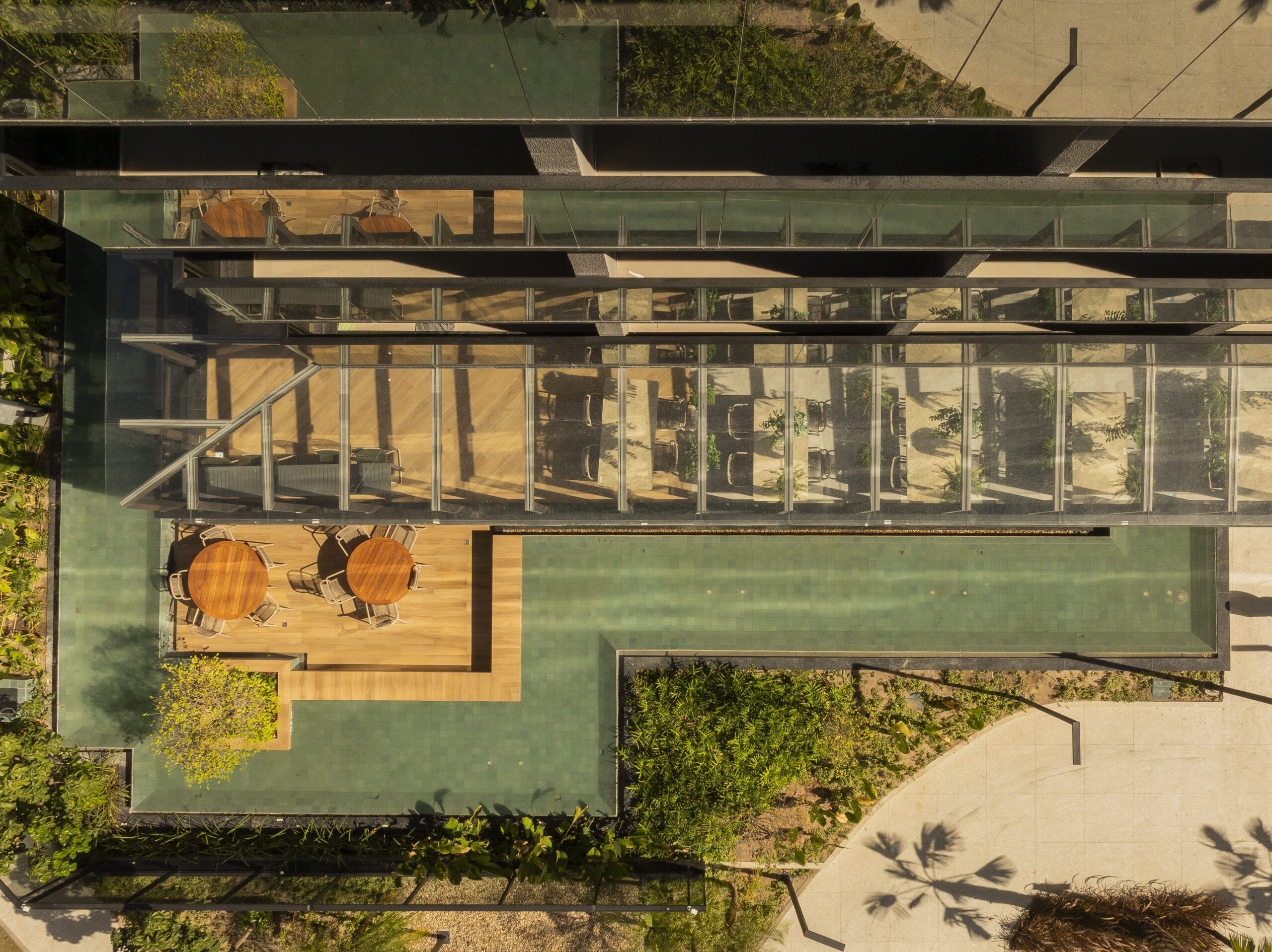 Um edifício moderno com terraço no telhado, área de estar ao ar livre e estrutura de vidro.