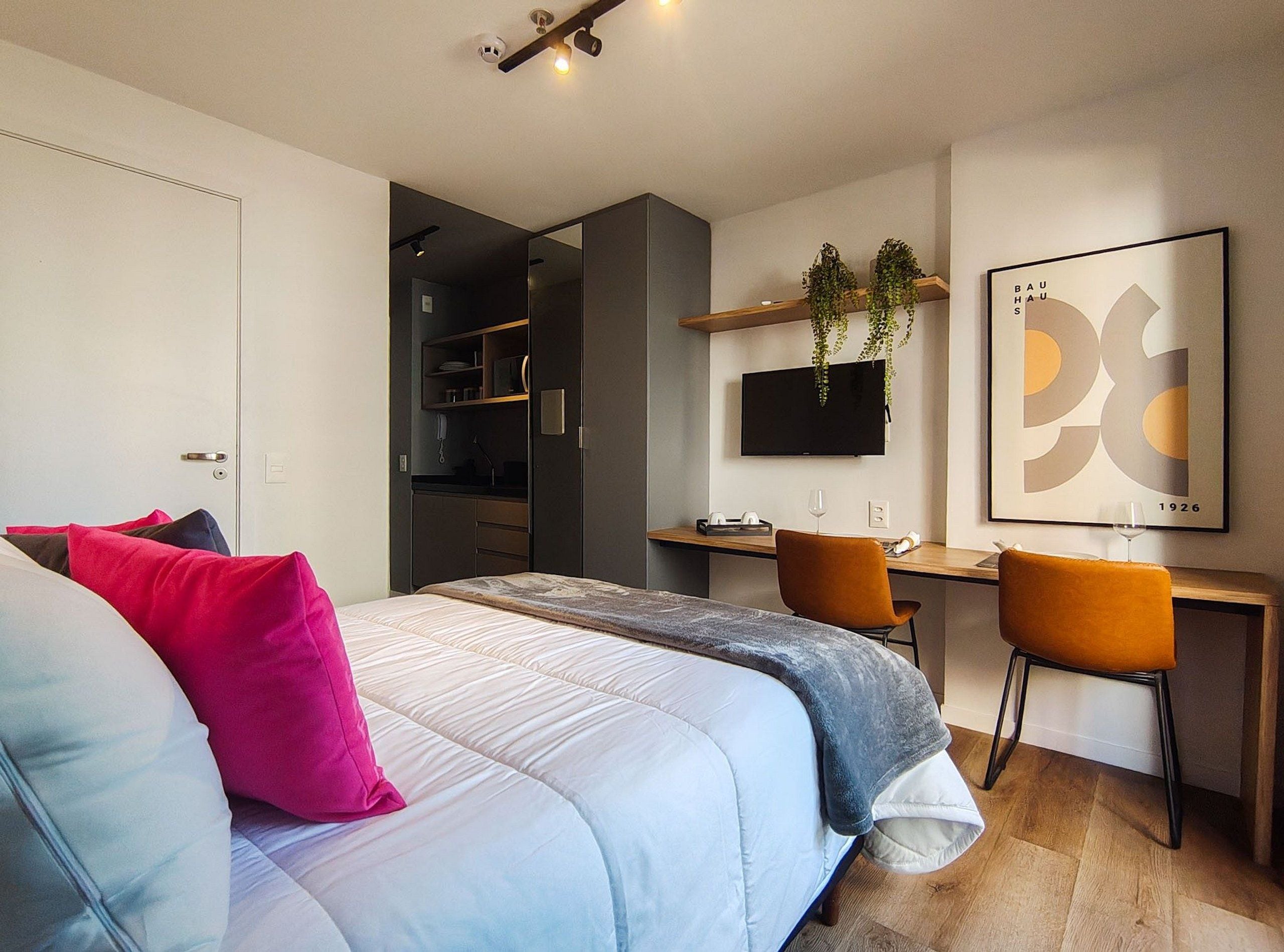 Una habitación de hotel moderna con una cama, un escritorio, una silla y un televisor.