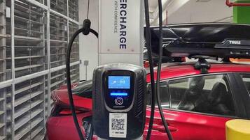 A parking garage with a charging station labeled 'Hypercharge' and a red car connected to it.