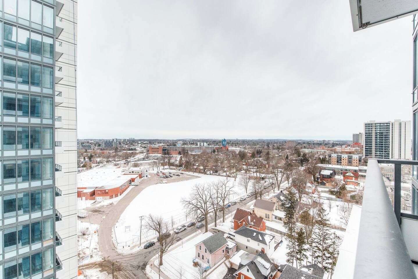 Un edificio de gran altura con varios pisos, ventanas amplias y vistas a un paisaje nevado con edificios residenciales y una ciudad lejana.