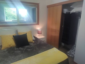 Un dormitorio con cama, mesita de noche, lámpara y armario.