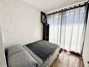 Ein Schlafzimmer mit einem Bett, einem Kleiderschrank und einem Fenster mit Vorhängen.