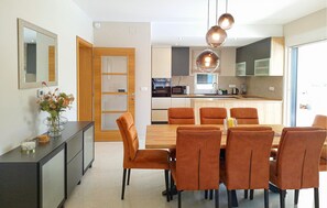 A modern kitchen with a central island, a dining area with six chairs, and a large mirror on the wall. - Lovely home in Malinska with private swimming pool, can be inside or outside (Malinska)