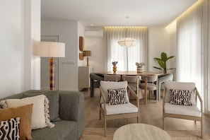 A modern living room with a sofa, chairs, a dining table, and a lamp. - Beachside Hideaway - Elegant Coastal Getaway (Peniche)