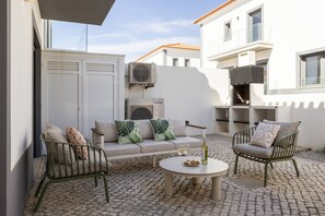 A patio with a sofa, two chairs, a round table, and a bottle of wine. - Beachside Hideaway - Elegant Coastal Getaway (Peniche)