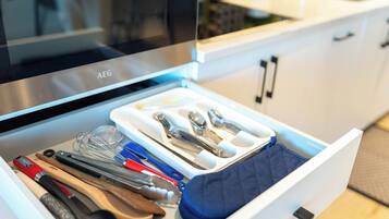 A kitchen drawer with utensils and a blue cloth.