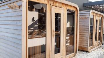 A wooden structure with large windows and a door, possibly a sauna or a similar facility.