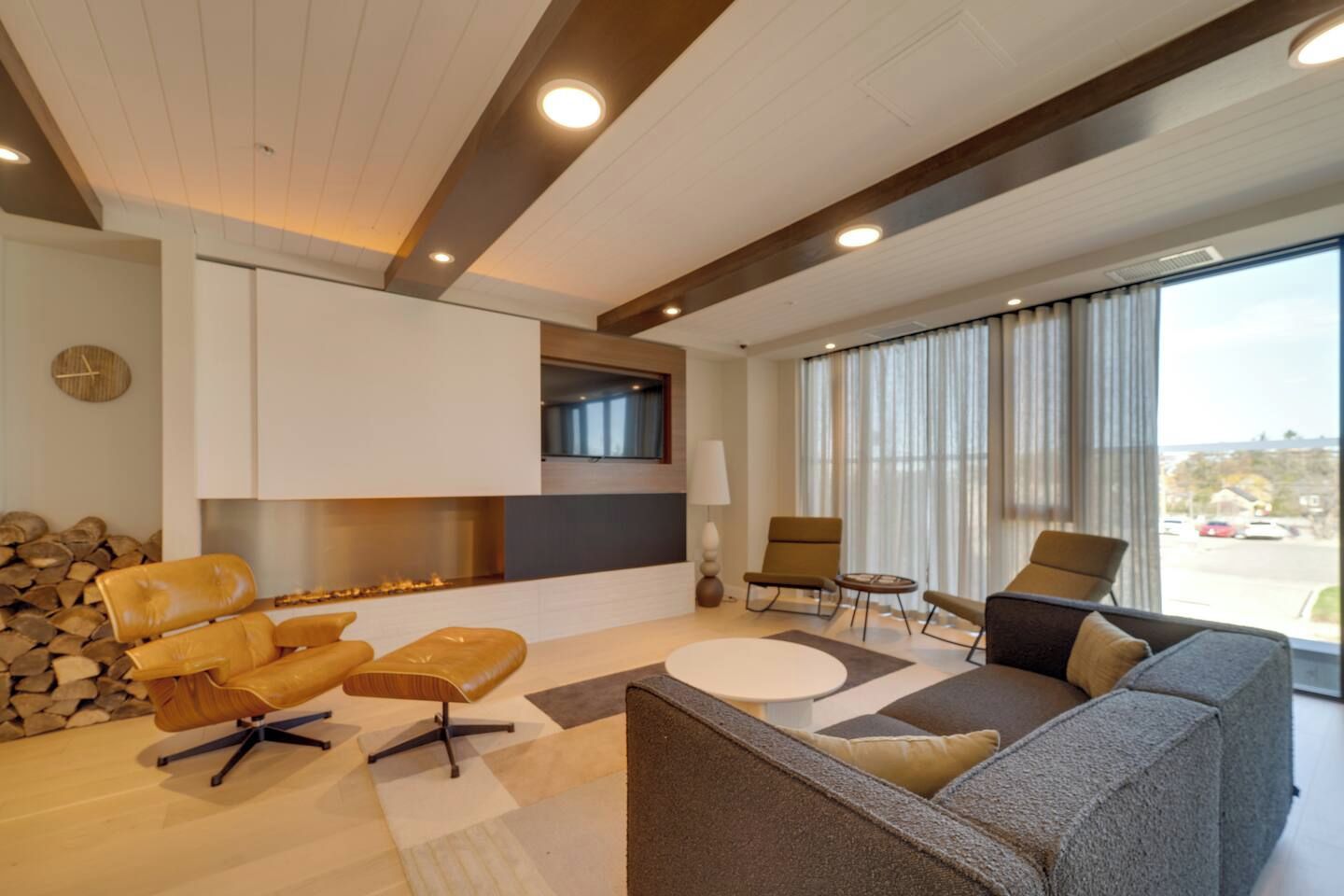 A modern living room with a fireplace, leather sofas, and a large window offering a view.
