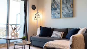 Un salon moderne avec un canapé gris, une petite table ronde et un lampadaire.