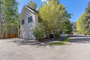 A two-story house with a garage, surrounded by trees and a clear sky. - Topaz Ketchum Retreat - pet friendly home (Ketchum)