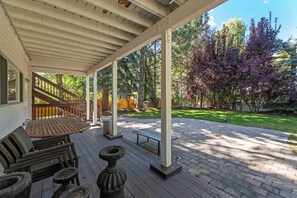 Une terrasse extérieure couverte, avec une table et des chaises en bois, un banc en bois et un foyer.