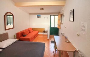 A room with a bed, a sofa, a table, and a chair. There is a window with curtains, a picture on the wall, and a notice on the wall. - 1 bedroom beautiful apartment in Duce (Duce)