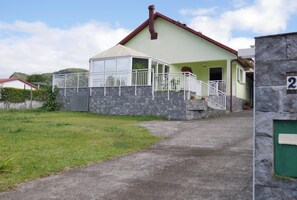 Une maison à deux étages avec un porche couvert et un mur en pierre.
