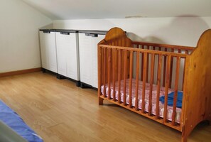 Une pièce comprenant un berceau en bois, une armoire et un lit.