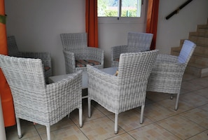 Een kamer met vier rieten stoelen rondom een klein tafeltje.