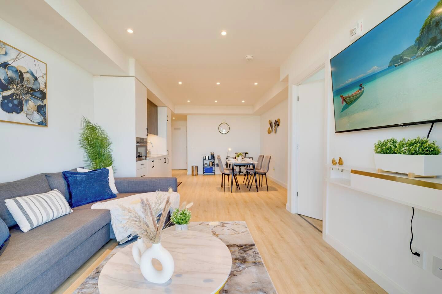 A modern living room with a sofa, coffee table, and a dining area with chairs and a table.