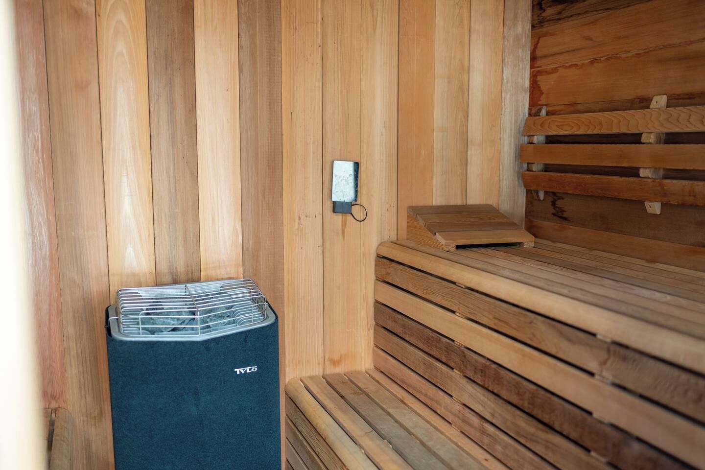 Una sauna con bancos de madera y una unidad de ventilación.
