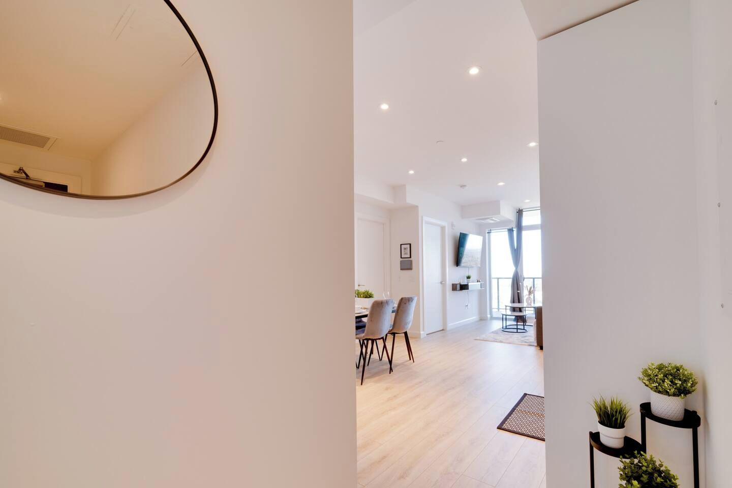A modern interior with a dining area, a flat-screen TV, and a large mirror.