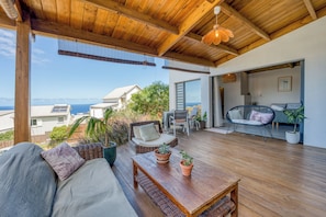 A wooden deck with a sofa, chairs, and a table, overlooking a scenic view. - Villa Lady seaview - Terrasse - Vue mer (Saint-Leu)