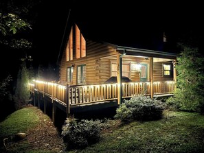 A wooden cabin with a covered porch and a deck, surrounded by greenery. - Little Bear Chalet - Mtn Views/Hot Tub/EV Charger (Bryson City)